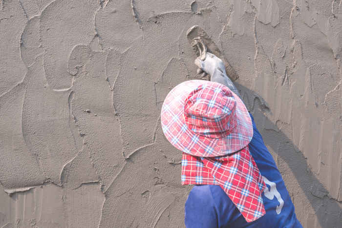 Person applying elastomeric paint on a stucco wall