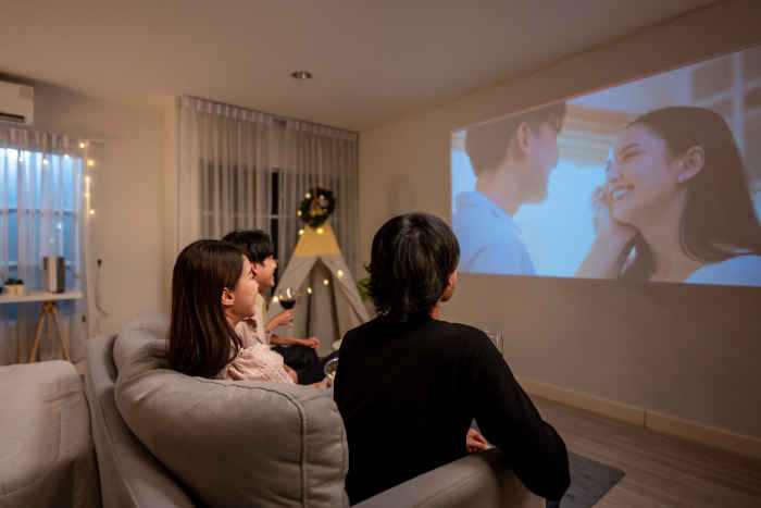 A group of people enjoying a movie night with a smart projector in a cozy living room.