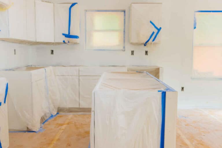 Kitchen cabinets masked off and prepped for painting, showcasing proper preparation techniques.