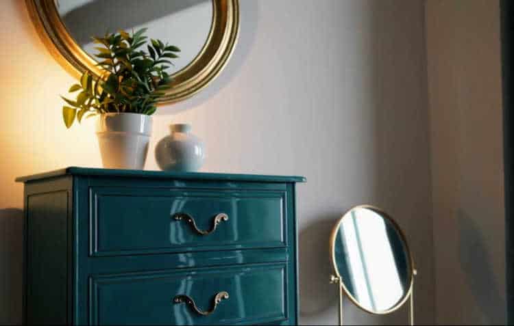 A vintage dresser painted in vibrant teal, styled with modern décor.