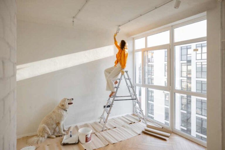 A person painting a large wall with a roller, taking on a big home painting project.