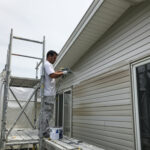 Professional painter spraying fresh coat of paint on aluminum siding in Ohio