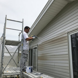 Professional painter spraying fresh coat of paint on aluminum siding in Ohio
