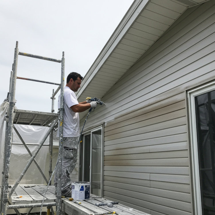 Professional painter spraying fresh coat of paint on aluminum siding in Ohio